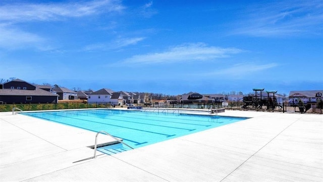 community pool featuring fence, a residential view, and a patio