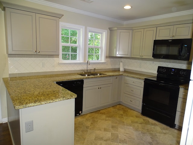 kitchen with black appliances, a sink, a peninsula, light stone countertops, and tasteful backsplash