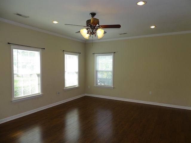 empty room featuring healthy amount of natural light, baseboards, dark wood-style floors, ornamental molding, and ceiling fan