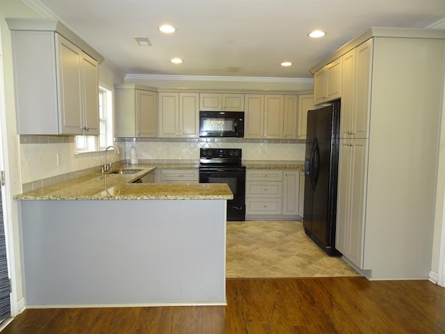 kitchen featuring black appliances, a sink, a peninsula, light stone counters, and light wood finished floors