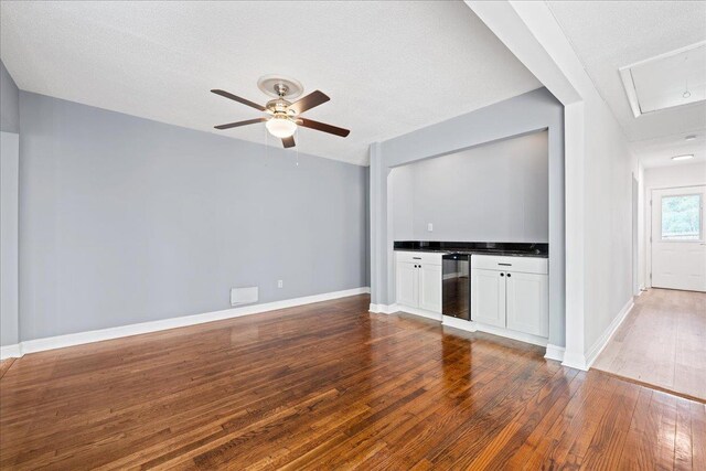 222 Woodview, Spartanburg, SC 29306 - unfurnished living room with wood finished floors, beverage cooler, ceiling fan, baseboards, and a textured ceiling