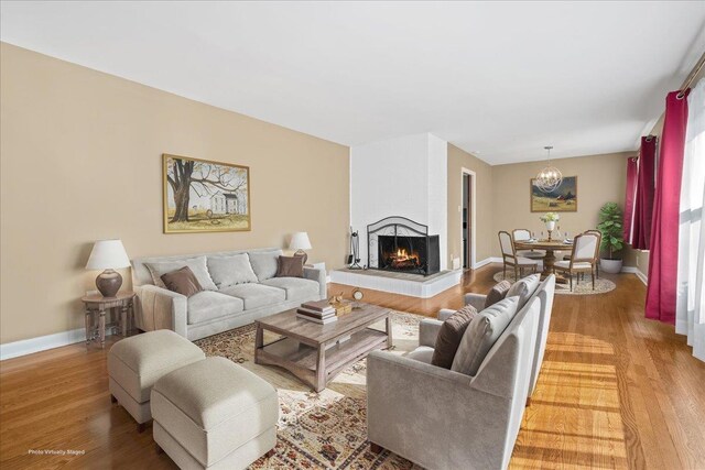 222 Woodview, Spartanburg, SC 29306 - living room featuring light wood-style flooring, a chandelier, a multi sided fireplace, and baseboards