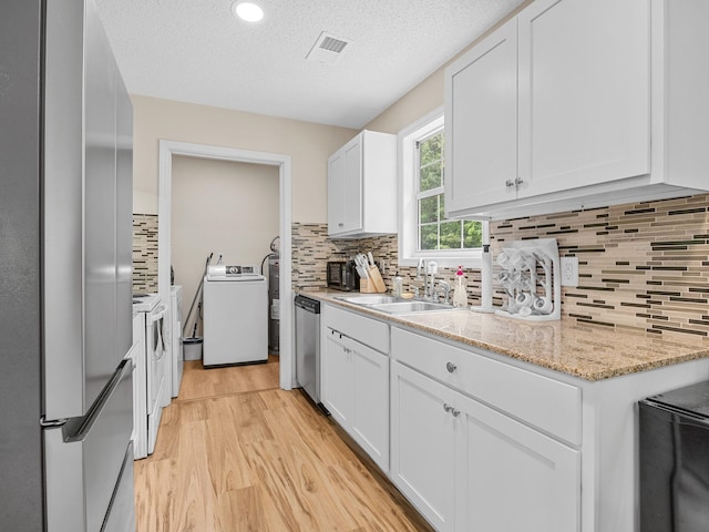 250 E Blackstock, Enoree, SC 29335 - kitchen featuring washer / clothes dryer, a sink, appliances with stainless steel finishes, light wood-style floors, and white cabinets