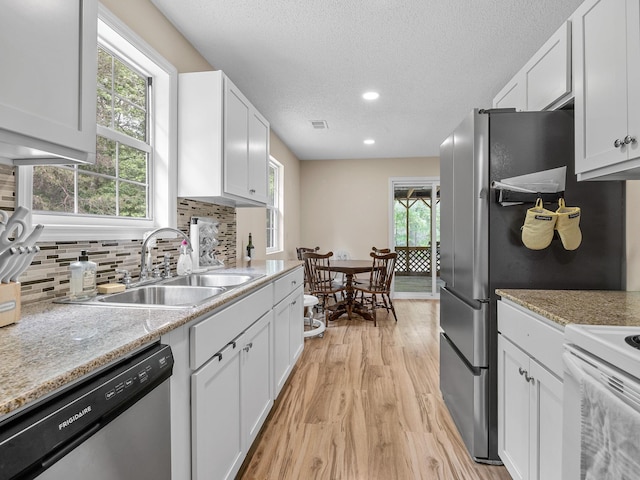 250 E Blackstock, Enoree, SC 29335 - kitchen with stainless steel dishwasher, a sink, light wood-style floors, decorative backsplash, and white cabinets