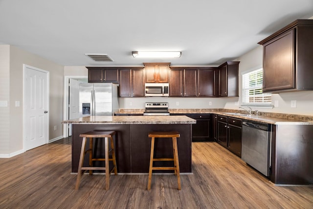 325 Victory, Moore, SC 29369 - kitchen with appliances with stainless steel finishes, dark wood-style flooring, a center island, dark brown cabinets, and a breakfast bar area