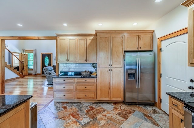 kitchen with stainless steel fridge, dark stone counters, backsplash, and recessed lighting