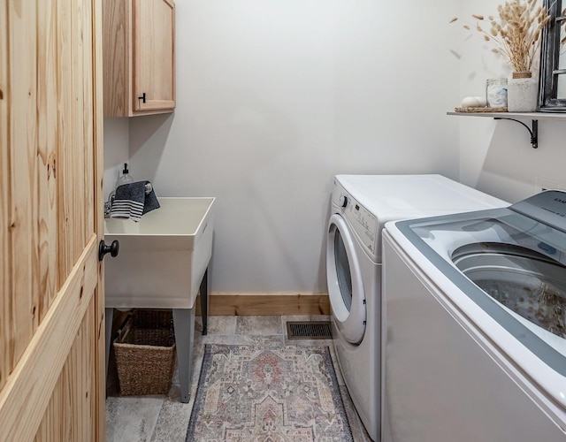laundry room featuring washing machine and dryer, cabinet space, and baseboards