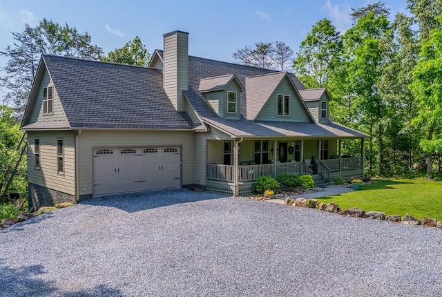 view of front facade with a porch, a garage, driveway, a front lawn, and a chimney