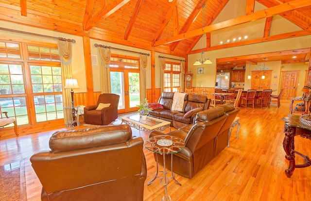 living area featuring beam ceiling, a wainscoted wall, wood ceiling, light wood-style flooring, and french doors
