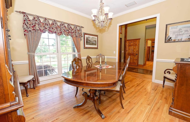 dining space featuring a chandelier, ornamental molding, and light wood finished floors