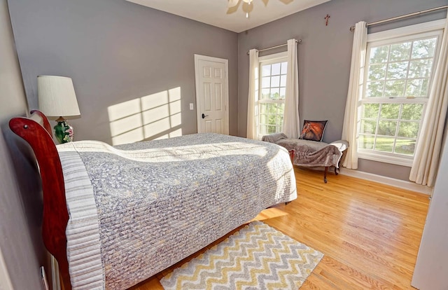 bedroom featuring wood finished floors, multiple windows, and baseboards