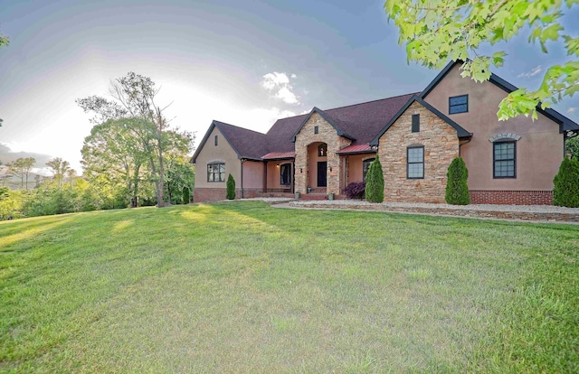 french country inspired facade featuring stone siding, stucco siding, and a front lawn