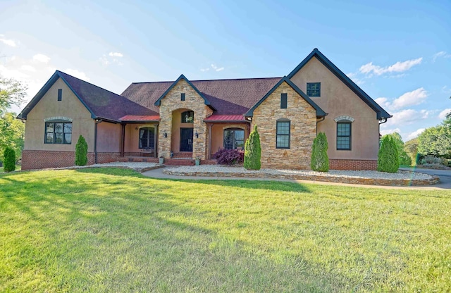 french country home featuring stone siding, stucco siding, a front lawn, and roof with shingles