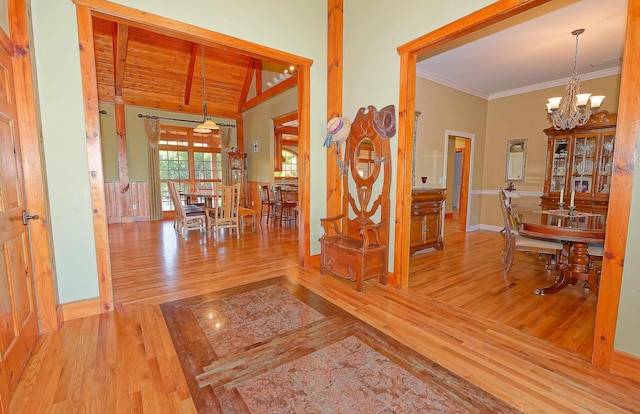corridor with wood finished floors, a chandelier, baseboards, and ornamental molding
