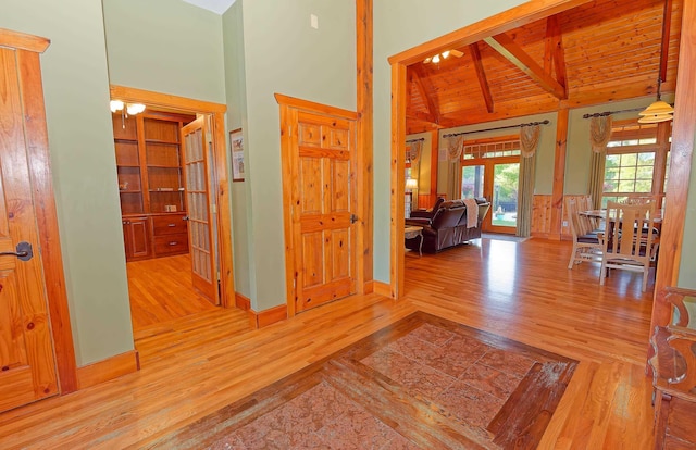 hallway with wood finished floors, beamed ceiling, high vaulted ceiling, french doors, and wooden ceiling