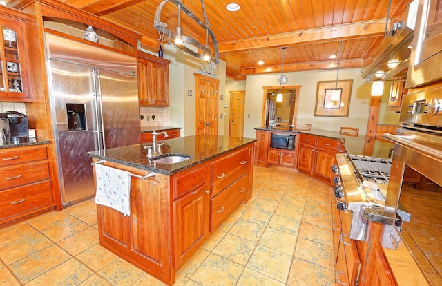 kitchen with a sink, wood ceiling, built in refrigerator, black microwave, and an island with sink