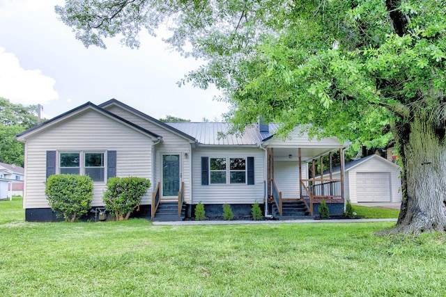 view of front of property with an outbuilding, a front lawn, a detached garage, metal roof, and a porch