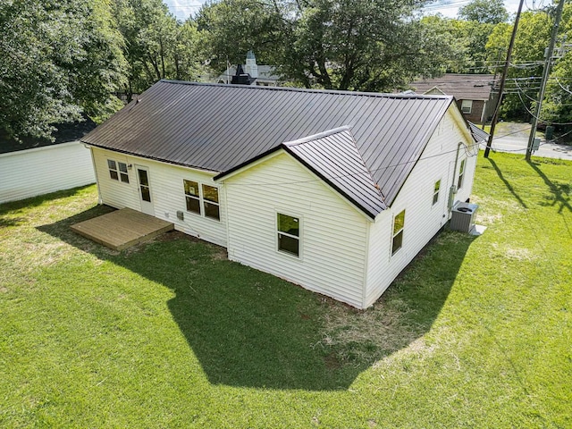 rear view of property with a yard, cooling unit, and metal roof