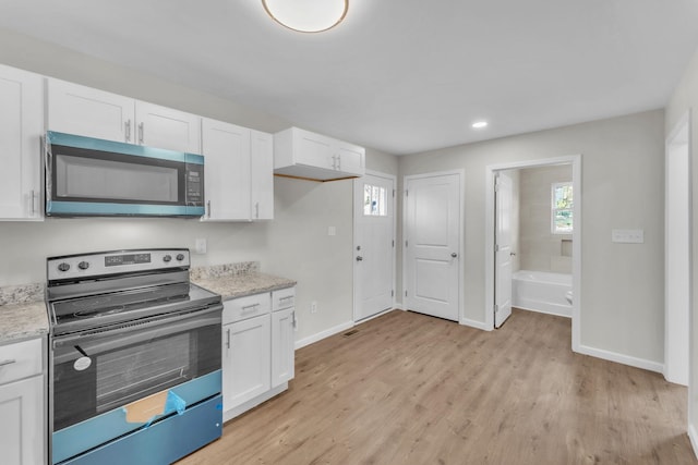 kitchen with stainless steel appliances, white cabinets, light wood-style floors, baseboards, and light stone counters