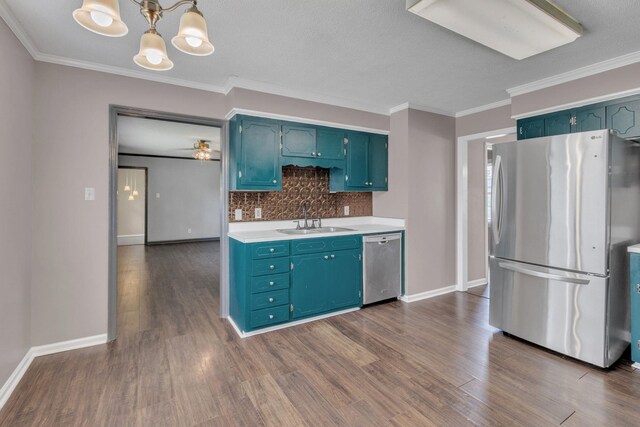 kitchen with appliances with stainless steel finishes, a sink, light countertops, dark wood-style flooring, and ornamental molding