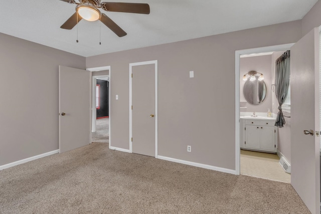 unfurnished bedroom featuring light carpet, a sink, ensuite bath, and baseboards