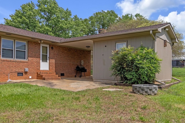 rear view of property featuring entry steps, a lawn, a patio, and brick siding