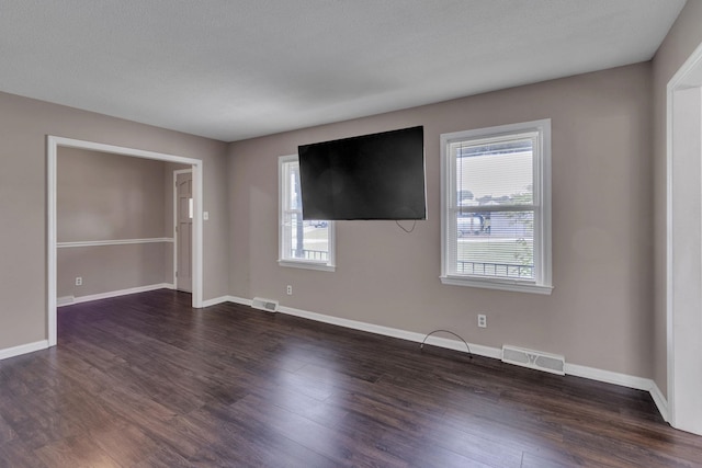 spare room featuring plenty of natural light, dark wood finished floors, and baseboards