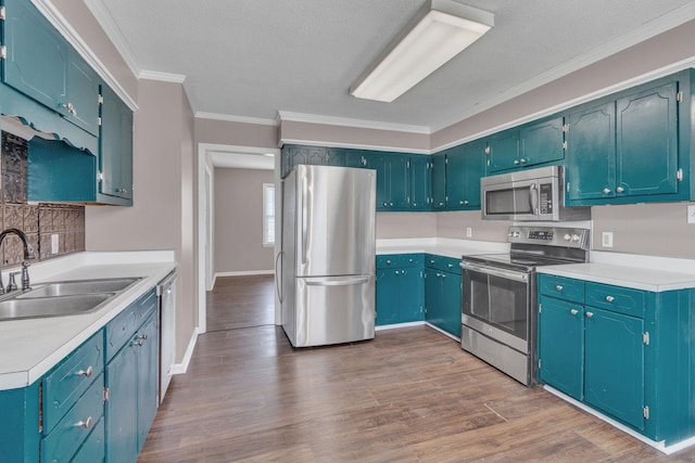 kitchen with stainless steel appliances, a sink, dark wood-style floors, ornamental molding, and light countertops