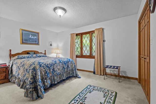 carpeted bedroom featuring a textured ceiling, baseboards, and a closet