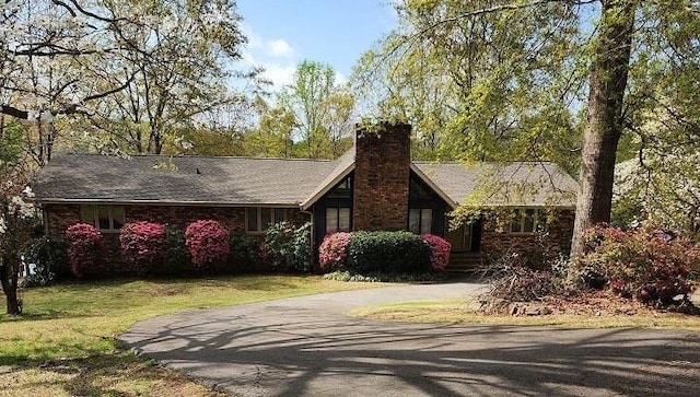 single story home featuring a chimney, driveway, and a front yard