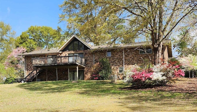 back of house featuring brick siding, a deck, stairs, and a lawn