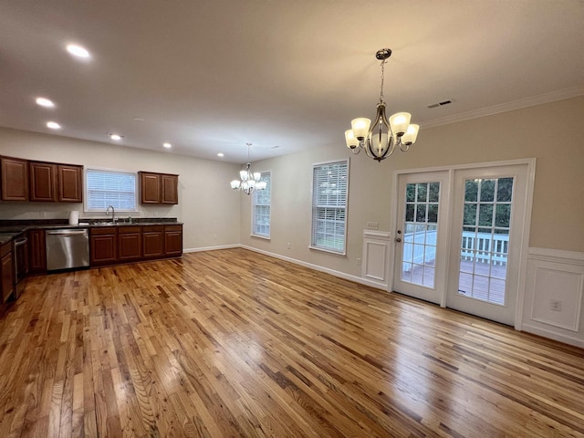 kitchen featuring a chandelier, stainless steel dishwasher, dark countertops, a sink, and light wood finished floors