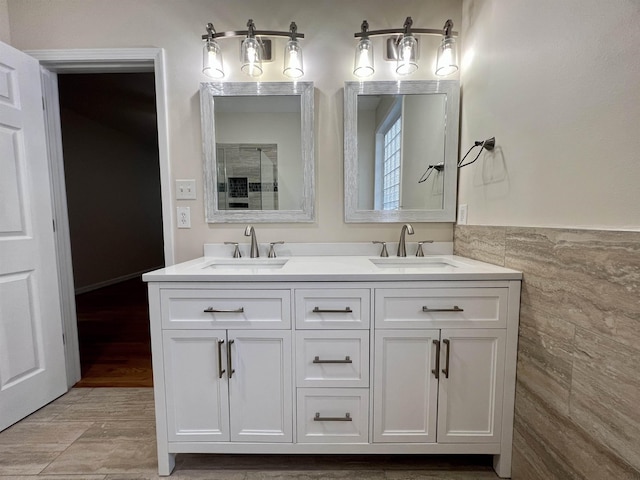 bathroom with tile walls, double vanity, and a shower