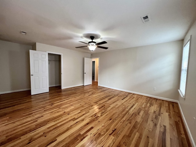 unfurnished bedroom featuring wood finished floors, baseboards, a ceiling fan, and a closet