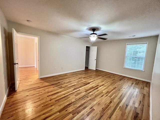 unfurnished room with light wood-style floors, ceiling fan, baseboards, and a textured ceiling