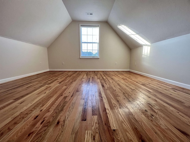 bonus room with hardwood / wood-style floors, lofted ceiling, and baseboards