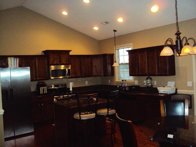 108 Dewfield, Boiling Springs, SC 29316 - kitchen with appliances with stainless steel finishes, vaulted ceiling, dark countertops, recessed lighting, and dark brown cabinetry