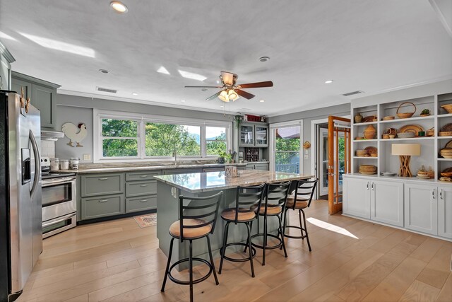 7 Hearthstone, Landrum, SC 29356 - kitchen featuring appliances with stainless steel finishes, plenty of natural light, light stone counters, light wood-type flooring, and ornamental molding