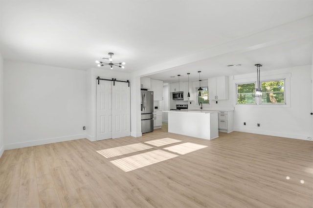 215 Blalock Rd, Boiling Springs, SC 29316 - unfurnished living room featuring a barn door, baseboards, a sink, and light wood-style floors