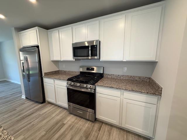 1214 Forestbrook, Spartanburg, SC 29303 - kitchen featuring appliances with stainless steel finishes, light wood finished floors, white cabinetry, dark stone counters, and baseboards