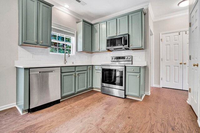 905 Morning Mist, Simpsonville, SC 29680 - kitchen with appliances with stainless steel finishes, crown molding, green cabinetry, a sink, and light wood finished floors
