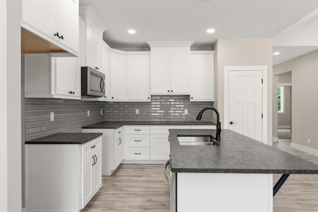 3135 E Croft, Spartanburg, SC 29302 - kitchen with stainless steel microwave, a sink, light wood finished floors, dark countertops, and a kitchen island with sink