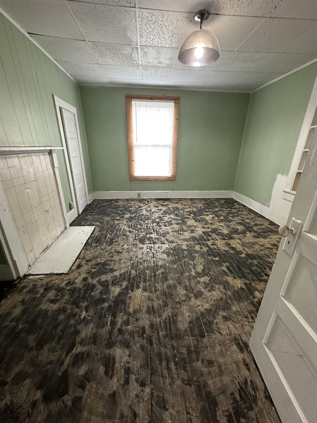 401 Elm, Gaffney, SC 29340 - unfurnished bedroom with baseboards, a paneled ceiling, wood walls, and dark wood-type flooring