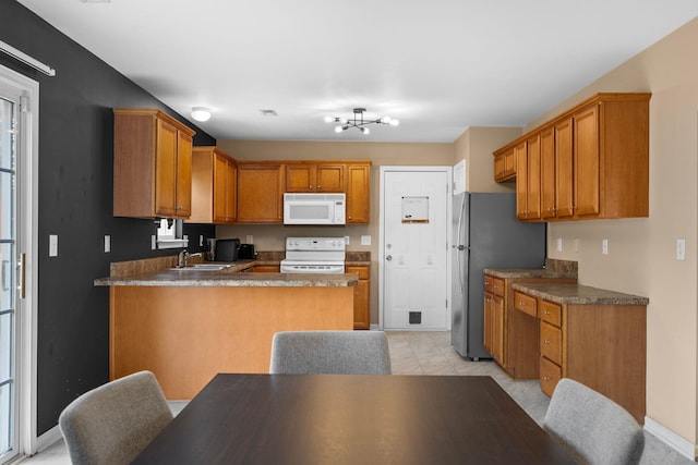 100 Maximus, Greer, SC 29651 - kitchen featuring white appliances, a peninsula, brown cabinets, dark countertops, and a sink