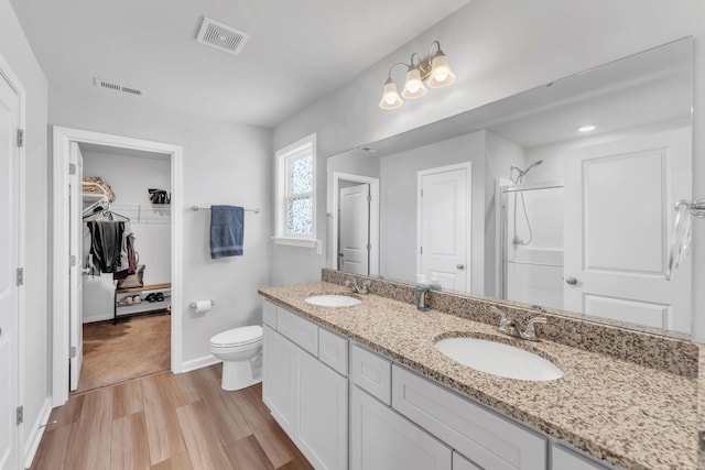 7096 Luna Mae, Boiling Springs, SC 29316 - bathroom featuring wood finished floors, walk in shower, double vanity, a walk in closet, and toilet