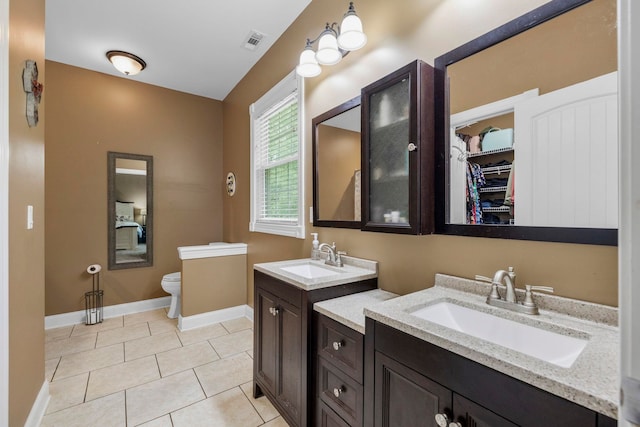 2131 Brockman Mcclimon, Greer, SC 29651 - bathroom featuring toilet, two vanities, baseboards, tile patterned flooring, and a walk in closet