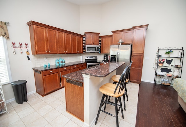 175 Castleton, Boiling Springs, SC 29316 - kitchen with appliances with stainless steel finishes, decorative backsplash, a towering ceiling, dark stone counters, and a kitchen bar