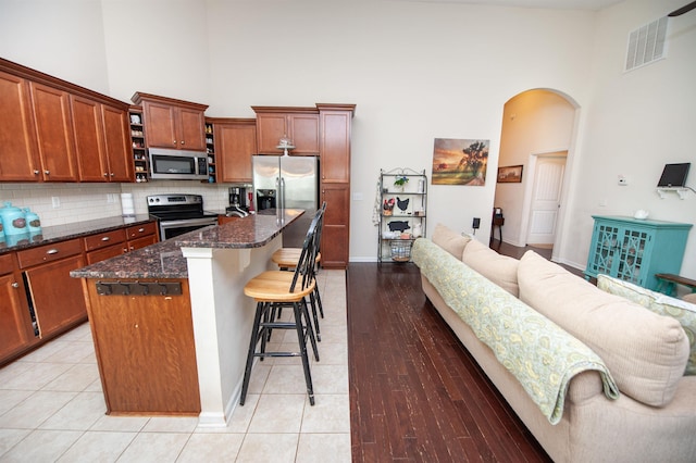 175 Castleton, Boiling Springs, SC 29316 - kitchen featuring appliances with stainless steel finishes, high vaulted ceiling, arched walkways, a kitchen bar, and tasteful backsplash