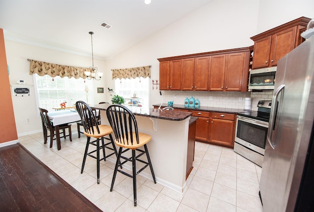 175 Castleton, Boiling Springs, SC 29316 - kitchen with stainless steel appliances, a kitchen breakfast bar, brown cabinetry, a chandelier, and decorative backsplash