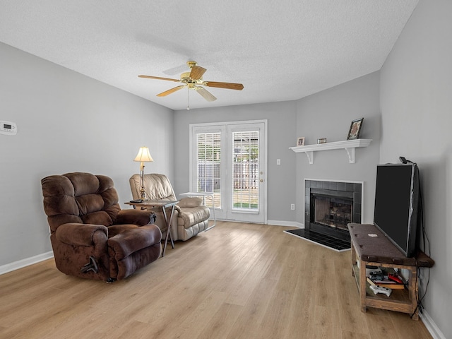 1156 Webber, Spartanburg, SC 29307 - living room with light wood-style floors, a tiled fireplace, a ceiling fan, baseboards, and a textured ceiling